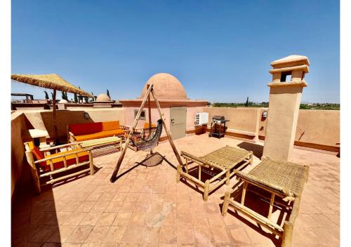 a group of chairs sitting on a patio at Duplex Luxe avec Rooftop, 3 Piscines, 2 Chambres, Atlas Golf Marrakech in Marrakech