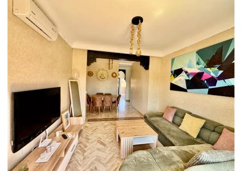 a living room with a couch and a flat screen tv at Duplex Luxe avec Rooftop, 3 Piscines, 2 Chambres, Atlas Golf Marrakech in Marrakech