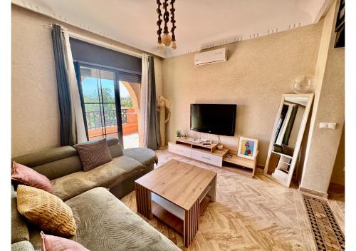 a living room with a couch and a table at Duplex Luxe avec Rooftop, 3 Piscines, 2 Chambres, Atlas Golf Marrakech in Marrakech