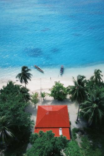 a red building on a beach with palm trees at Palambak Paradise Resort Pulau Banyak in Pulau Palambakbesar