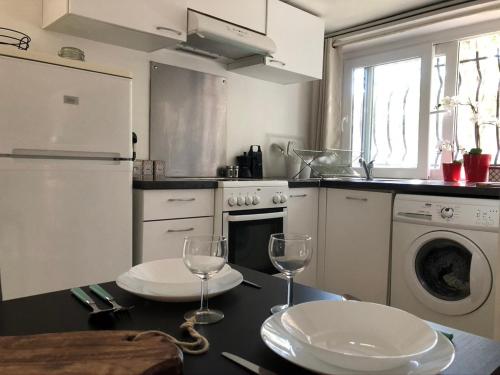 - une cuisine avec une table avec deux assiettes et des verres à vin dans l'établissement Appartement en rez de villa, à Montpellier