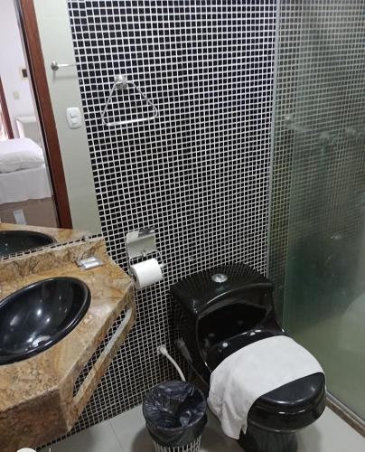 a bathroom with a black toilet and a sink at Rede Andrade Porto Seguro in Porto Seguro