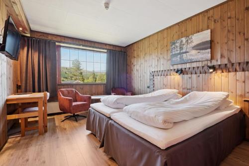 a bedroom with two beds and a desk and a chair at Heia Gjestegård in Grong