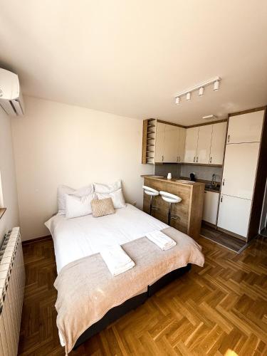 a bedroom with a large bed and a kitchen at Limpio Apartman 2 in Belgrade