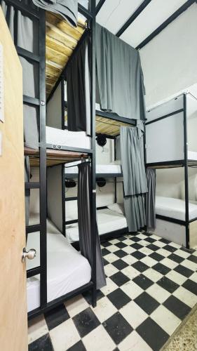 a room with three bunk beds on a checkered floor at Baku Laureles Hostel in Medellín