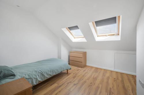 a bedroom with two windows and a bed and a wooden floor at Spacious 4 bed, 3 bath house - Free parking in Thornton Heath