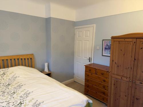 Un dormitorio con una cama y una cómoda de madera. en Queens Road Llandudno, en Llandudno