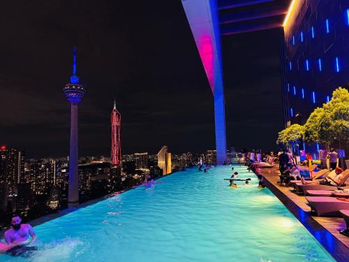 a swimming pool with people in the city at night at THE PLATINUM KLCC by COZY STAY in Kuala Lumpur