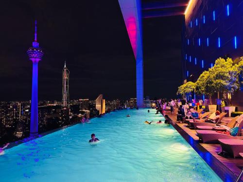 a swimming pool with people in the city at night at THE PLATINUM KLCC by COZY STAY in Kuala Lumpur