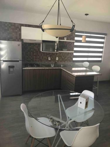 a kitchen with a glass table and white chairs at La Hidalgo, Departamento A in Chapala