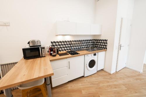a kitchen with a counter and a washer and dryer at Modern AC Studio in the Heart of Chartrons in Bordeaux