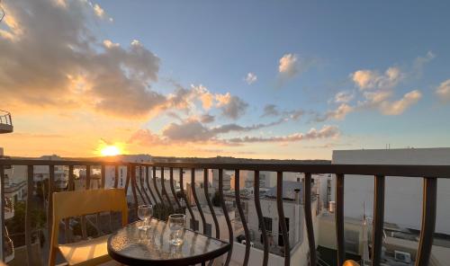 a balcony with two tables and chairs with the sunset at Seaside Serenity Retreat in St Paul's Bay