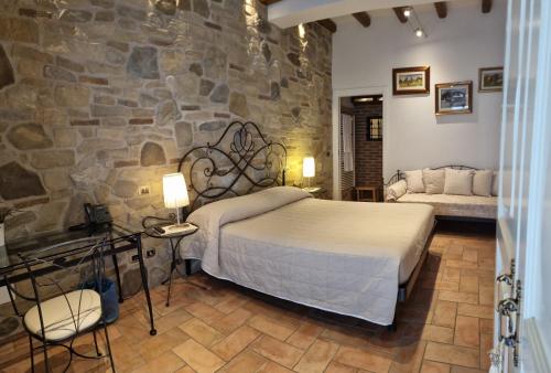 a bedroom with a bed and a stone wall at Locanda Gli Ulivi in Monteveglio