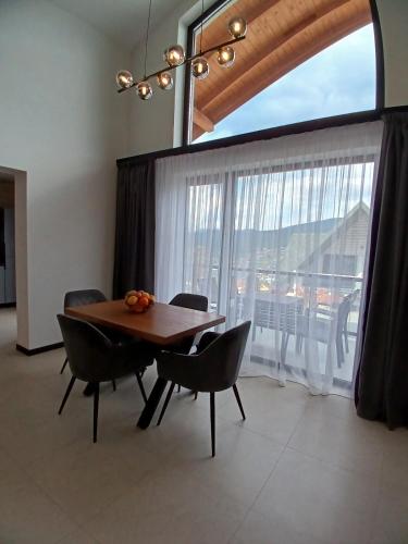 a dining room with a table and chairs and a large window at EcoBerghaus - Котеджне містечко in Bukovel