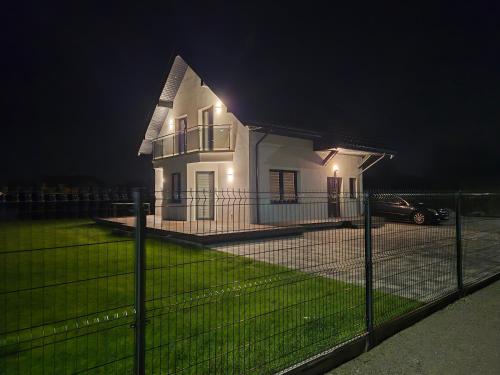a white house with a fence in front of it at night at Apartament Słoneczny Zakątek Grzybowo in Grzybowo