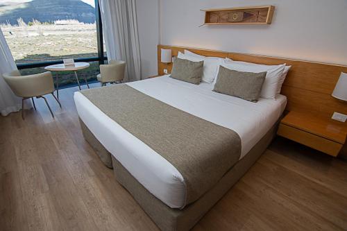 a large bed in a hotel room with a window at Design Suites Calafate in El Calafate