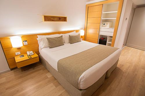a bedroom with a large bed and a night stand at Design Suites Calafate in El Calafate