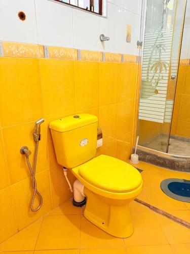 a yellow bathroom with a shower and a yellow toilet at Utopia Hikka in Hikkaduwa