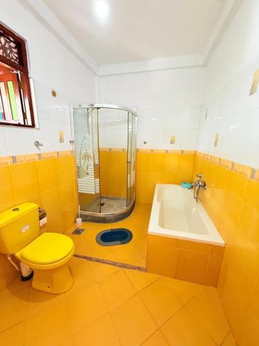 a bathroom with a yellow toilet and a shower at Utopia Hikka in Hikkaduwa