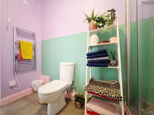 baño con aseo y estante con toallas en Quirky Apartment Close to town centre and FREE parking, en Cheltenham