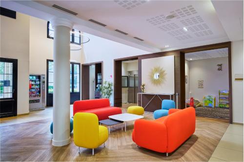 a lobby with colorful chairs and a table at Adagio Serris Val d'Europe in Serris