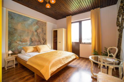 ein Schlafzimmer mit einem Bett und einem Gemälde an der Wand in der Unterkunft Art'e Boutique Rooms in Băile Tuşnad