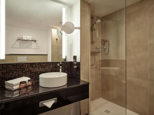 a bathroom with a sink and a shower at Leonardo Hotel Hamburg City Nord in Hamburg