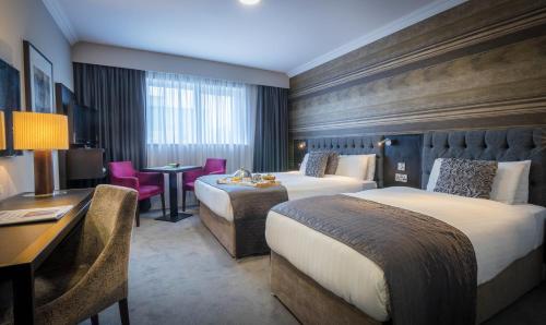a hotel room with two beds and a desk at Talbot Hotel Wexford in Wexford