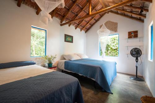 a bedroom with two beds and two windows at Refugio Ilha Grande in Angra dos Reis