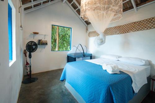 a bedroom with a bed with blue sheets and a window at Refugio Ilha Grande in Angra dos Reis
