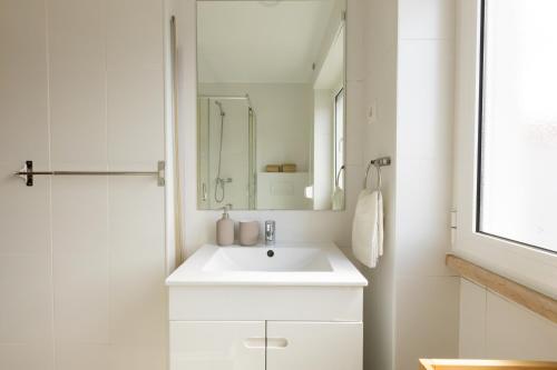 a white bathroom with a sink and a mirror at BV 01 Apartment in Amadora
