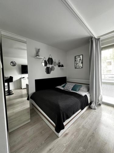 a bedroom with a black bed and a window at Charming Apartament in Płock
