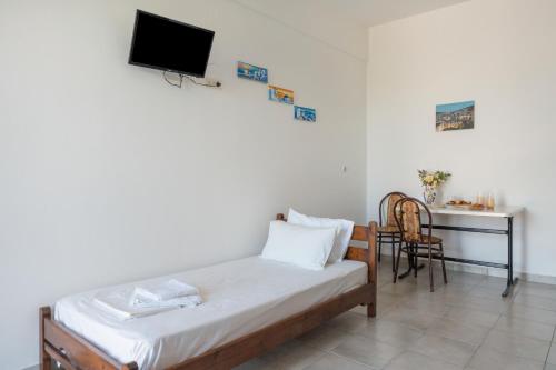 a room with a bed and a desk and a television at Frantzis studio 1 in Páloi