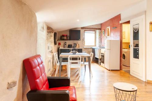 a living room and kitchen with a table and a red chair at Gîte L'Atelier in Saint Martin sur Lavezon