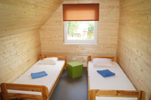 2 Betten in einem Holzzimmer mit Fenster in der Unterkunft Mežezera stāsts in Pļaviņas