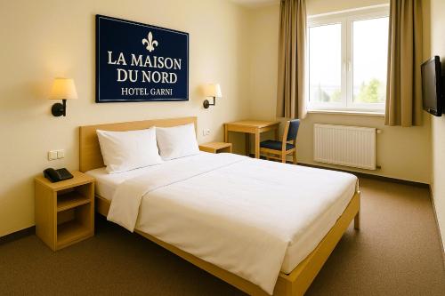 a hotel room with a large bed and a sign at LA MAISON DU NORD - Hotel Garni in Cuxhaven