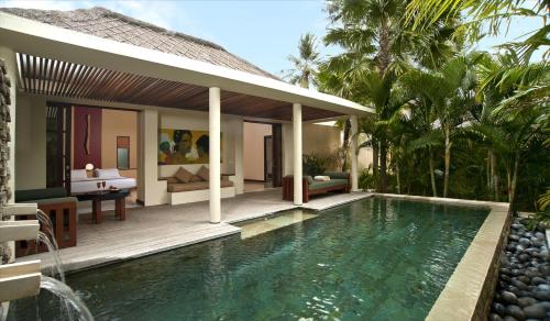 a villa with a swimming pool in front of a house at Qunci Villas Resort in Senggigi 