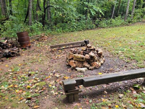 a pile of logs sitting next to a park bench at Modern Cabin on wooded 20 acres with scenic view in Nancy, KY in Nancy