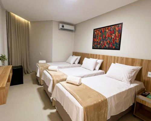 a hotel room with three beds and a painting on the wall at Arrey Express Hotel - Picos in Picos