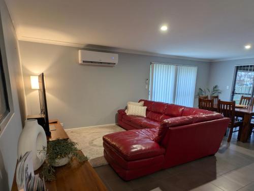 a living room with a red couch and a table at Spacious 4x2 Southwest Gem Perfect for Two Families, Steps from Top Attractions with Fun Spaces for Kids, separate areas for Adults and Big Savings in Vasse