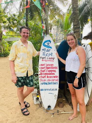 a man and a woman standing next to a surfboard at Star Rest Surf Camp Arugambay in Arugam Bay