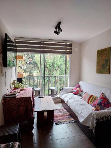 a living room with a couch and a table and a window at Depto cerca playa in La Serena