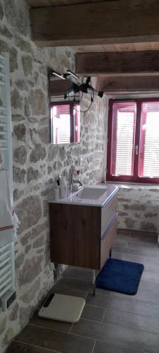 a bathroom with a sink and a stone wall at Chambre double chez l'habitant 