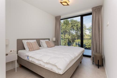 a bedroom with a large bed and a large window at Faro Greenpark, Cadzand-Bad Penthouse in Cadzand