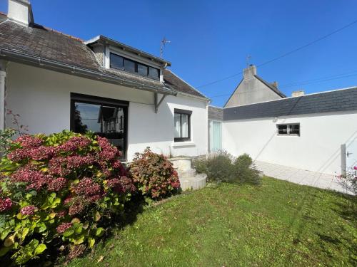 ein weißes Haus mit rosa Blumen im Hof in der Unterkunft L'Abri du Rouget, 5 minutes à pied de la plage du Trez-hir, vacances en famille in Plougonvelin
