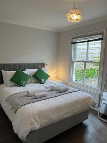 ein weißes Schlafzimmer mit einem großen Bett und grünen Kissen in der Unterkunft Ground Floor Flat BishopAuckland in Bishop Auckland