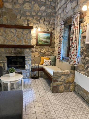 a stone walled room with a couch and a fireplace at Zsóka Fogadója in Szentantalfa