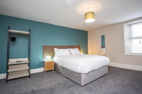 une chambre avec un grand lit et un mur bleu dans l'établissement Livingston Retreat 4bed Home Wi-Fi Parking, à Uphall