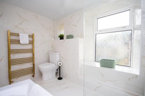 une salle de bain blanche avec toilettes et fenêtre dans l'établissement Livingston Retreat 4bed Home Wi-Fi Parking, à Uphall