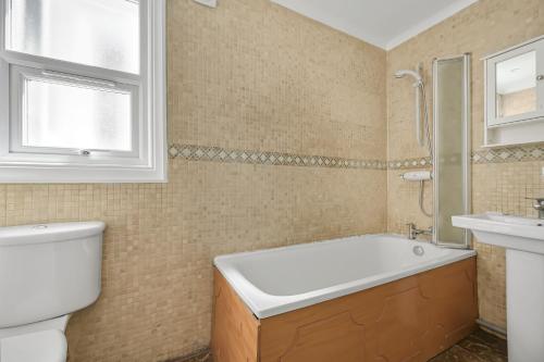 a bathroom with a tub and a toilet and a sink at Contractors - Businesses - Families - Long term Stays - Free parking in Thornton Heath